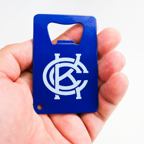 A hand holding a blue bottle opener with a white KCC logo