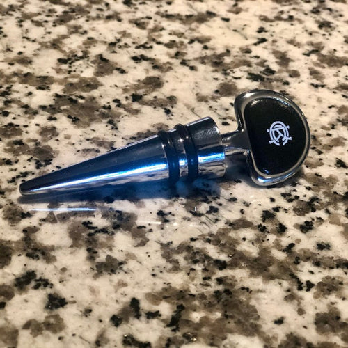 Bottle stopper with white KCC Logo laying on a granite countertop