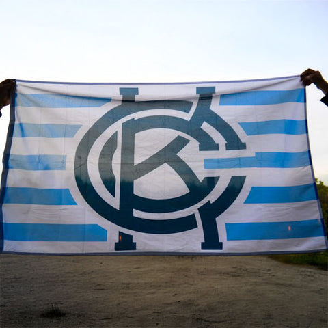 A flag featuring a blue and white striped design with a prominent KCC logo in the center.
